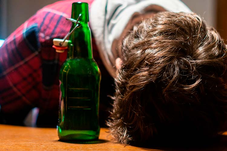 мужчина спит за столом рядом с бутылкой пива