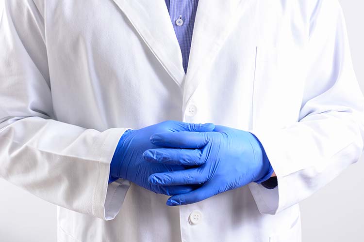 мужчина врач в белом халате и синих перчатках